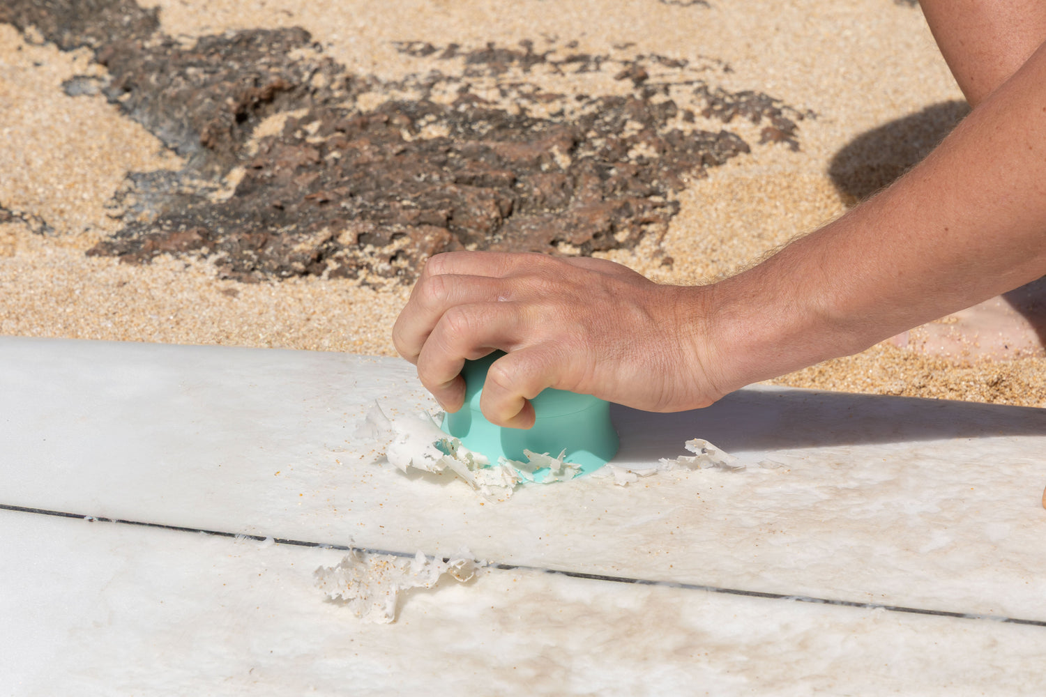 Kauila's surf wax scraper scraping wax off a surf board.